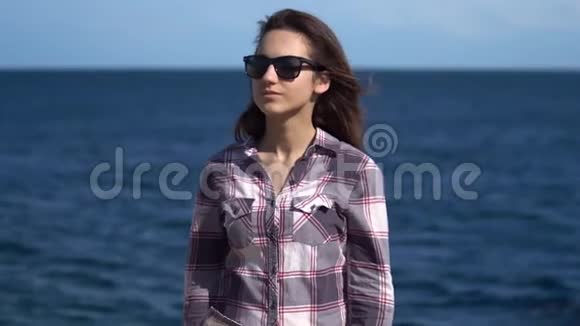 海背景的年轻女子阳光明媚的天气里戴太阳镜的女孩探索周围的自然视频的预览图