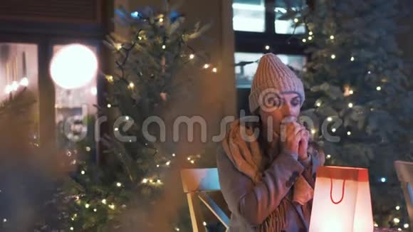 冬天女人坐在户外咖啡馆的露台上看着一个带礼物的袋子为她在那里找到的东西感到高兴这就是视频的预览图