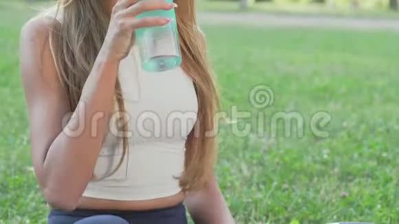 健康健康的女人在公园里做瑜伽的时候喝水视频的预览图