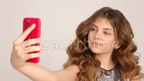 美丽的少女手拿着智能手机在镜头前自拍视频的预览图