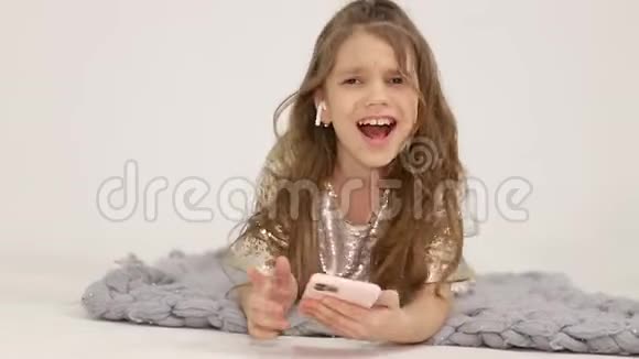 小女孩在智能手机上听音乐女孩在家里的床上唱歌视频的预览图