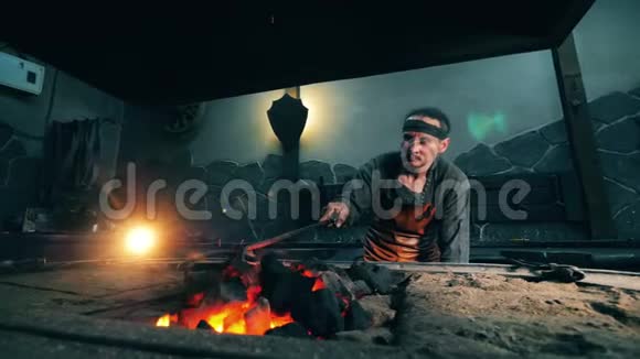 一个人用金属扑克在火中移动煤车间铁匠锻铁视频的预览图