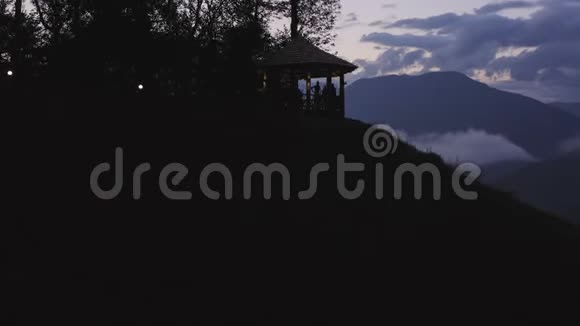 游客在山上的露台上放松有美丽的夜晚城市视频的预览图