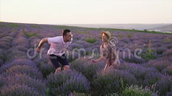 年轻夫妇在开花薰衣草地跳跃动作缓慢视频的预览图