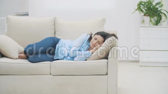慢点满意的黑发女人睡在家里的沙发上女人正在做着令人愉快的梦4K视频的预览图