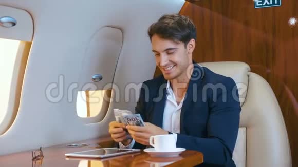 穿西装的帅哥在私人飞机上飞行时会把钱扔出去享受生意上的成功和胜利视频的预览图