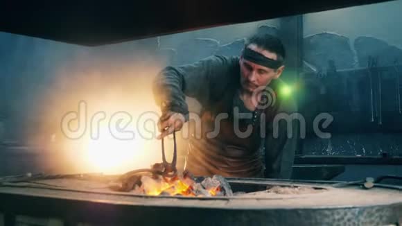 一个铁匠用火钳把一把金属刀在火里视频的预览图
