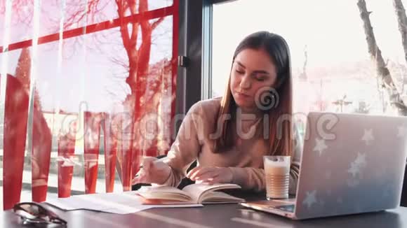 一位商务女士在一家带笔记本电脑的咖啡馆工作视频的预览图