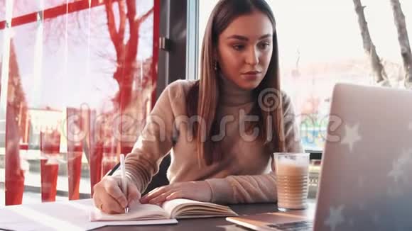 一位商务女士在一家带笔记本电脑的咖啡馆工作视频的预览图