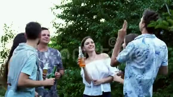 朋友群叮叮当当瓶子喝啤酒人们在公园里跳舞拥抱晚会视频的预览图