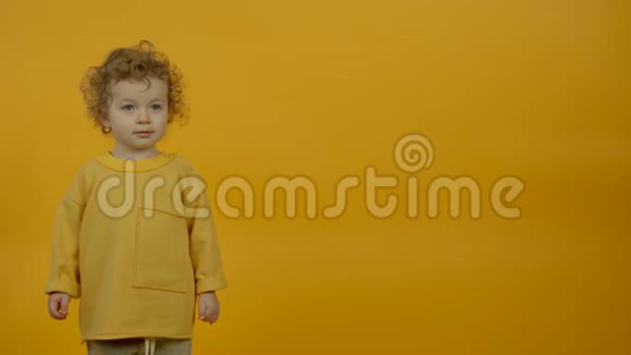 可爱的卷发孩子在黄色背景下跳舞视频的预览图