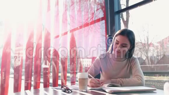 一个漂亮的黑发女孩正在笔记本上写字视频的预览图
