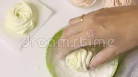 一个女人正在准备棉花糖连接两半卷成糖霜从特写镜头中射出视频的预览图