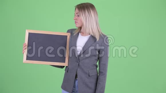 年轻的金发碧眼的女商人拿着黑板竖起大拇指视频的预览图