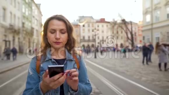 年轻女子使用智能手机沿着老街走着对她在那里看到的东西有很强的情感反应视频的预览图
