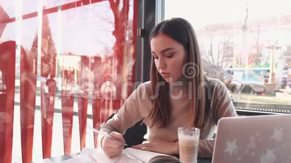 这位漂亮的黑发女士正在咖啡馆里学习视频的预览图