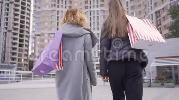 两个女朋友带着购物袋走在街上的后景无忧无虑的生活方式购物狂视频的预览图