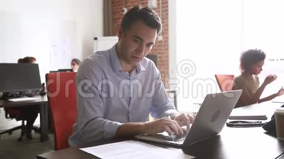 中年员工在笔记本电脑上看协议文件打字视频的预览图