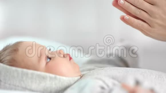 特写可爱的小宝宝躺在床上拍手重复到妈妈的手臂一起玩耍侧视视频的预览图