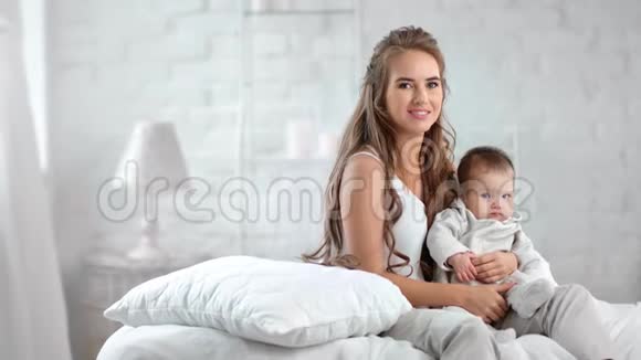 美丽的母亲摆姿势小可爱的小男孩包围豪华的白色房间内部视频的预览图