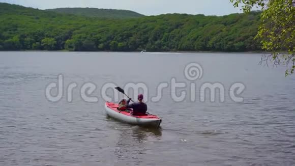 一个年轻人和他的小儿子坐在湖或海湾里的一艘充气大皮艇上视频的预览图