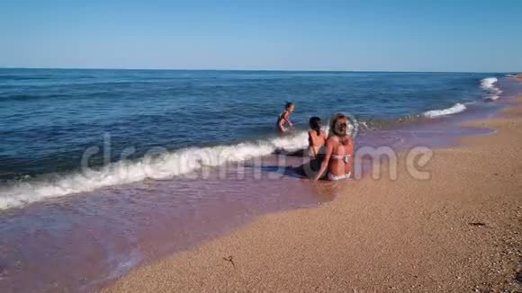 一家人坐在沙滩上的海浪中视频的预览图