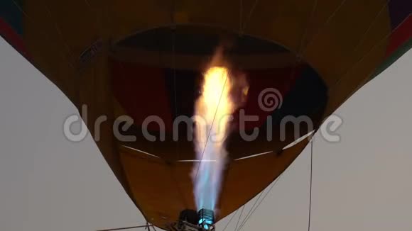 关闭彩色热气球中的丙烷气体燃烧机在地面上空飞行的视频视频的预览图