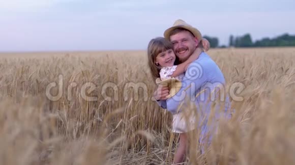 家庭关系快乐的男人快乐地拥抱快乐的小女孩在成熟的时候用成熟的小麦在田野上微笑视频的预览图