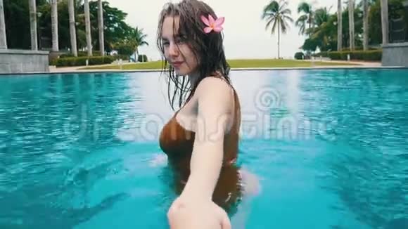 一位头发湿漉漉的年轻女子牵着男朋友在游泳池里的手视频的预览图