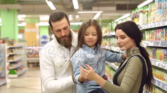 幸福家庭的肖像可爱的小女孩在杂货店里选择果汁视频的预览图