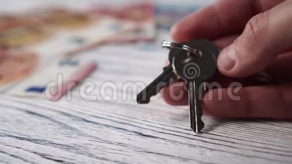 白色木制桌子上的欧元钞票背景上的新住房钥匙视频的预览图