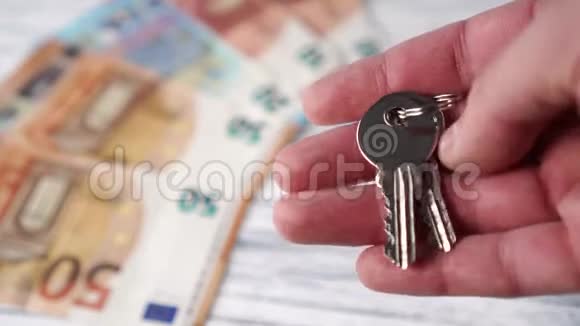 白色木桌上一堆欧元钞票背景上崭新闪亮的房子钥匙视频的预览图