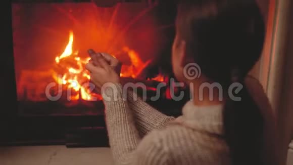 4k调调视频年轻女子晚上坐在壁炉旁暖和双手视频的预览图