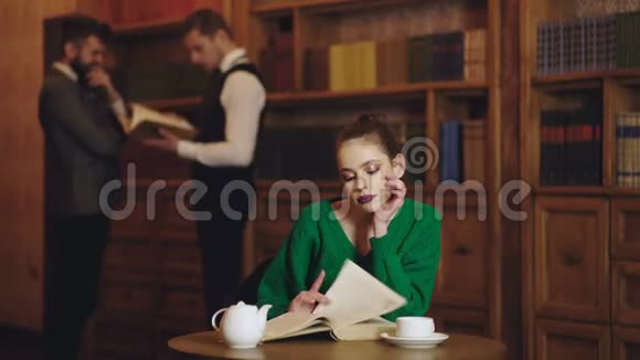 图书馆里的女人看书从杯子里喝咖啡文学咖啡馆有可爱的女孩和男人背景学生视频的预览图
