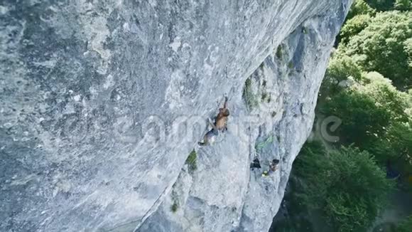 俯视图广角镜头强壮肌肉男子攀岩者动态攀登垂直悬崖视频的预览图