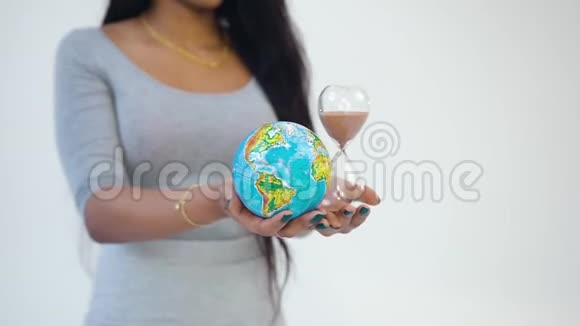 不知名的现代非洲裔美国年轻女性手中拿着沙钟和地球仪视频的预览图