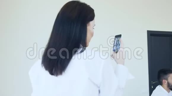穿西装的年轻商务女性在手机上拍摄视频并评论办公室里发生的一切事情视频的预览图