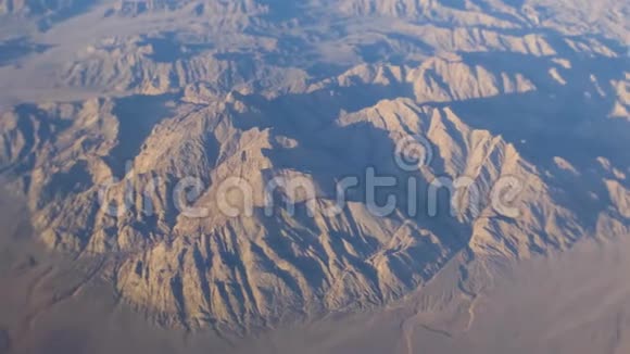 飞越沙漠中的岩石山脉从平面窗口的视图空中镜头视频的预览图