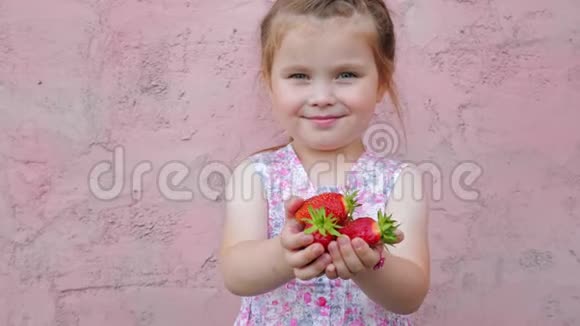 小可爱的漂亮女孩伸出手拿着草莓浆果视频的预览图