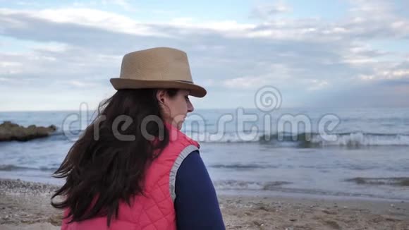 坐在海边的女人转过头看着镜头慢吞吞地走着视频的预览图