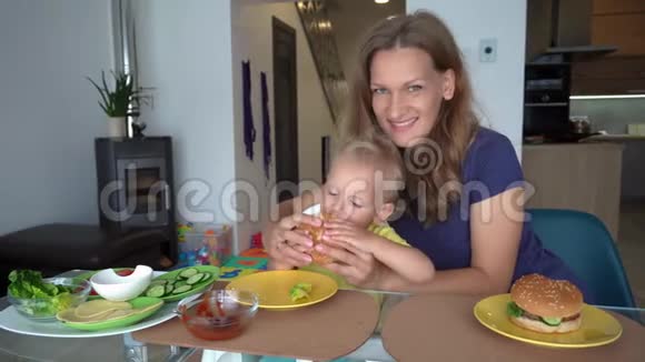 微笑的母亲用大汉堡喂小儿子万向节运动视频的预览图