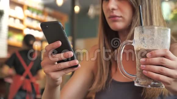 一个女孩的特写肖像女性喝一杯鸡尾酒拍一部4k的智能手机视频的预览图