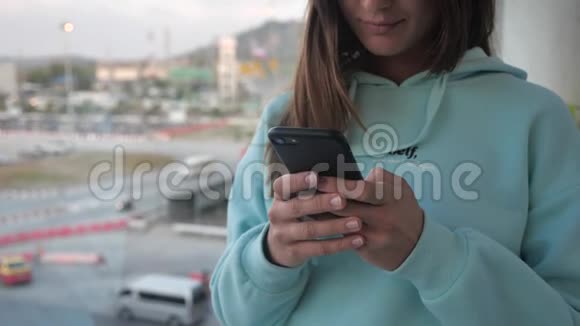 在机场窗口附近使用智能手机的年轻女性带背包的快乐欧洲女人在终端使用移动应用程序4K视频的预览图