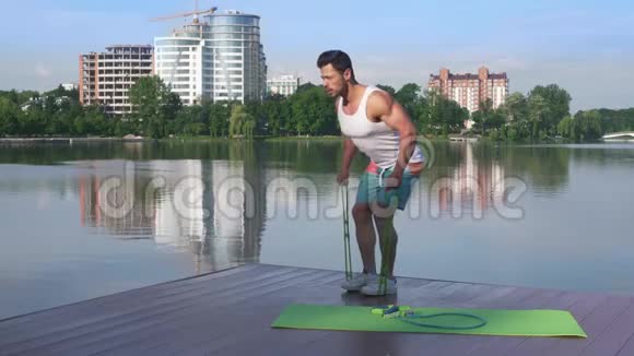 运动员和肌肉男在湖边伸展橡皮筋视频的预览图