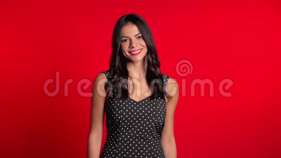 漂亮的年轻拉丁女孩长发站在红色的工作室背景上视频的预览图