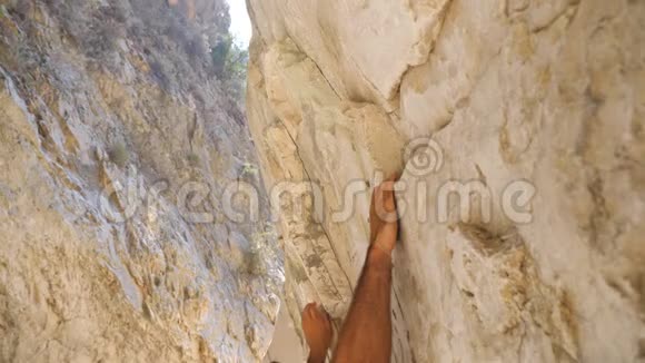 年轻的肌肉男在岩石上小心翼翼地攀爬强壮的人在摇滚巅峰上奋起努力登山者视频的预览图