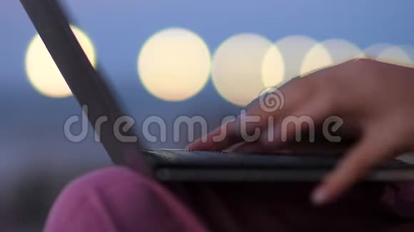 女人深夜在户外用笔记本电脑打字视频的预览图