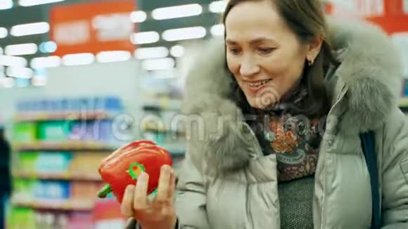 超市里的一个女人选了一个红辣椒圣诞节买蔬菜视频的预览图