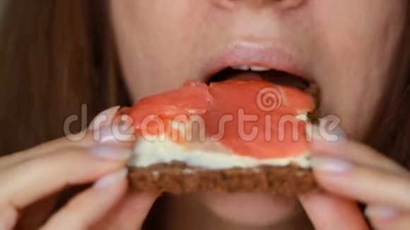 一个吃红鱼黄油三明治的女人的特写镜头女孩咬鲑鱼三明治视频的预览图