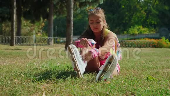坐在草地上的小女孩穿上了她的旱冰鞋视频的预览图